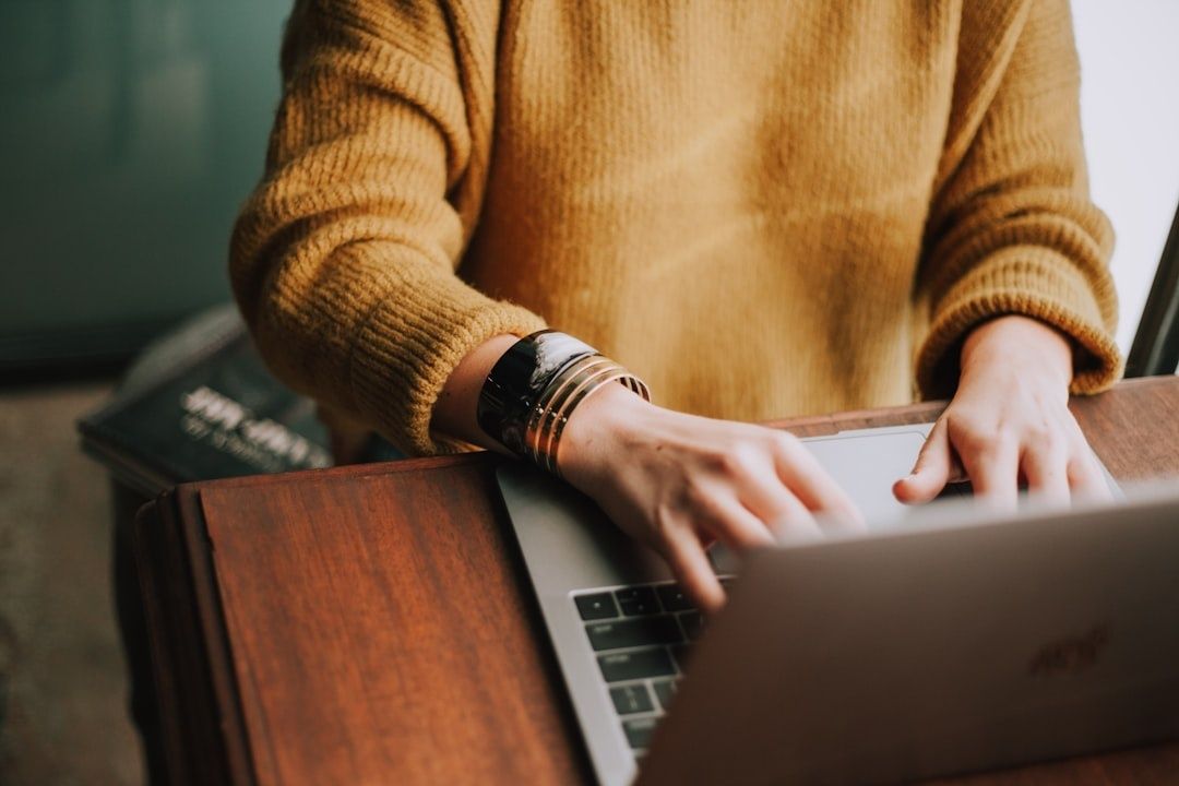 Person using a laptop at a wooden desk, representing focused newsletter reading